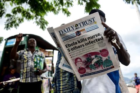 Man reads Daily Trust newspaper on EVD outbreak in Nigeria