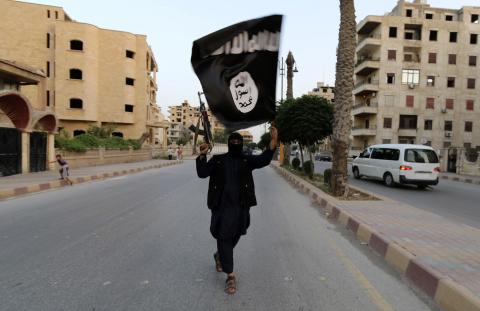 A member of the Islamic State of Iraq and the Levant (ISIL) waves the group's flag in Raqqa, Syria