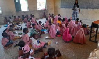 Pupils, Teacher Sit On Bare Floor, Mat In Adamawa School 