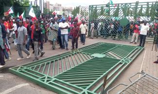 BREAKING: Protesters Pull Down National Assembly Gate In Abuja, Force Their Way Into Premises  